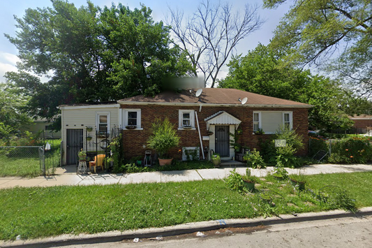 Two-story brick house with a front yard and trees on a sunny day